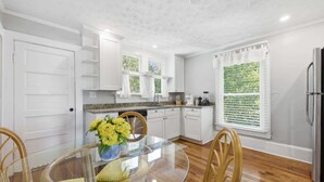 A kitchen with white cabinets, a glass dining table, and a window with blinds. - The Pearl, 2 Unit Stay for 10 (St. Augustine)
