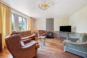 Una sala de estar con sofá, sillones, chimenea y televisor.