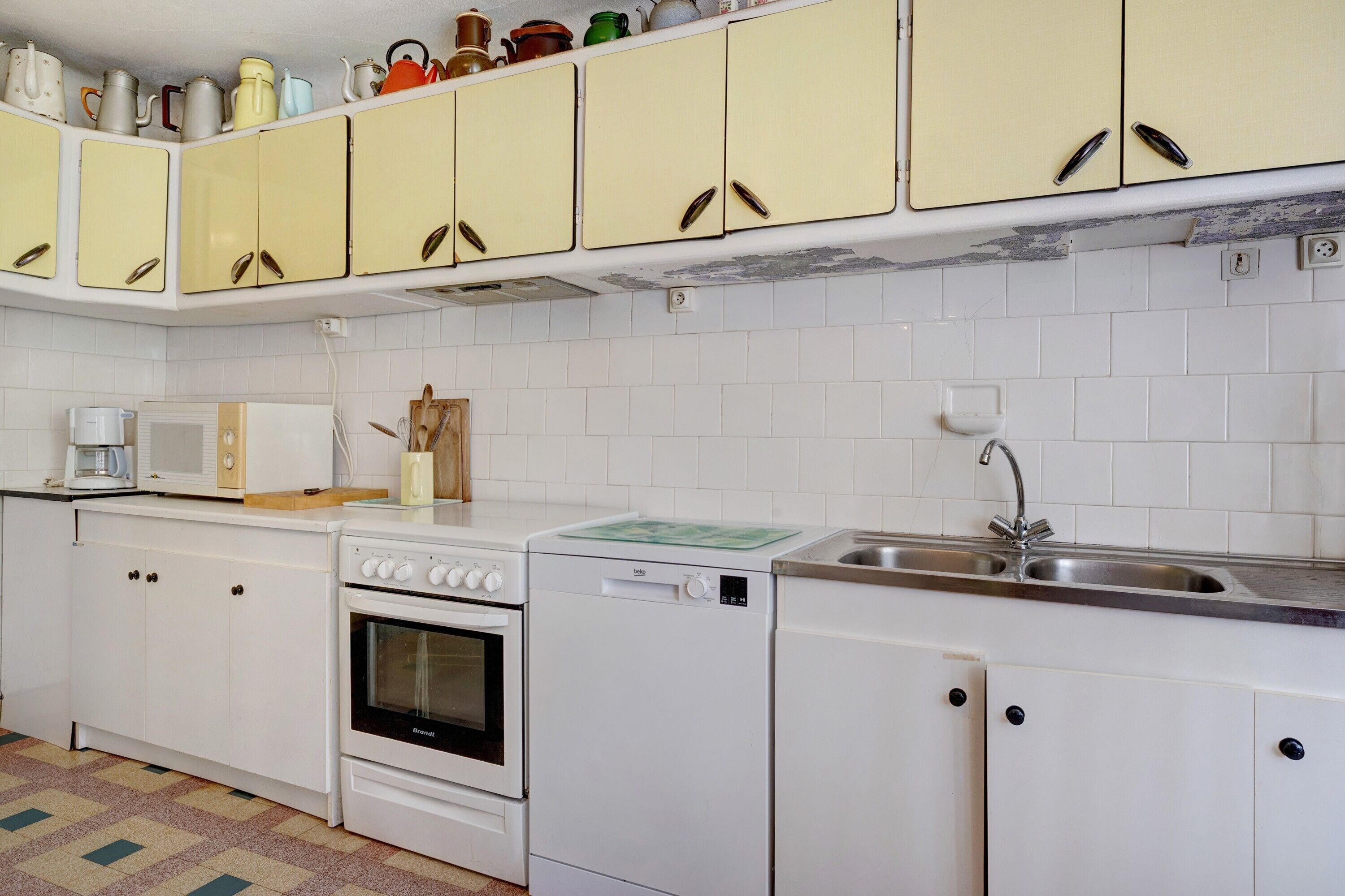 Eine Küche mit weißen Schränken, einer Mikrowelle, einem Backofen, einem Geschirrspüler und einem Spülbecken.