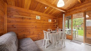 Een houten blokhut interieur met een eethoek, een bank en uitzicht door de deur.