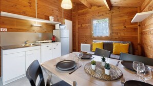 A wooden cabin with a kitchen, dining area, and a window. - Chalet "Confort 16" with Terrace and Shared Pool (Saint-Gervais)