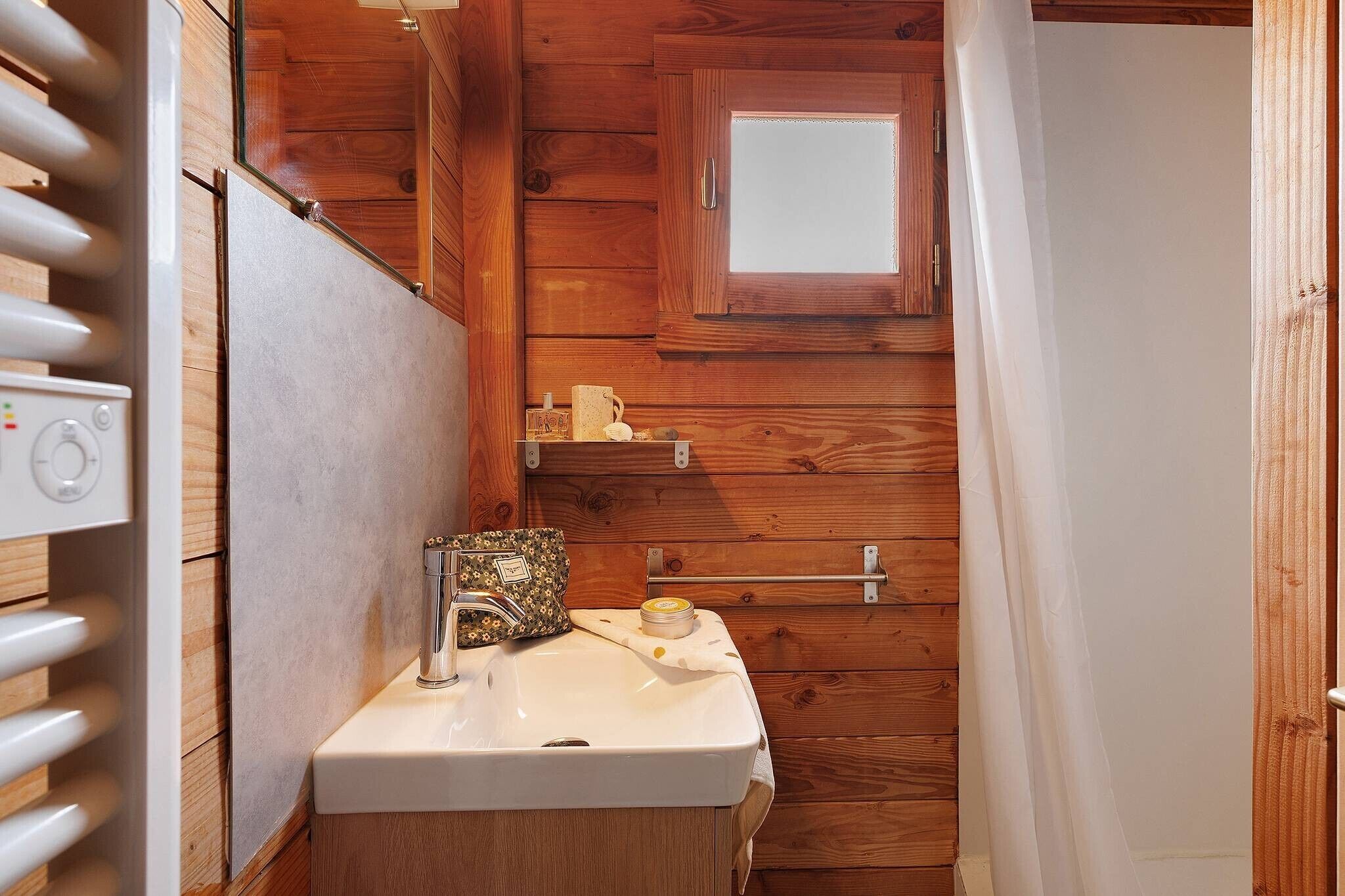 A wooden cabin bathroom with a white sink, a small window, and a towel rack.