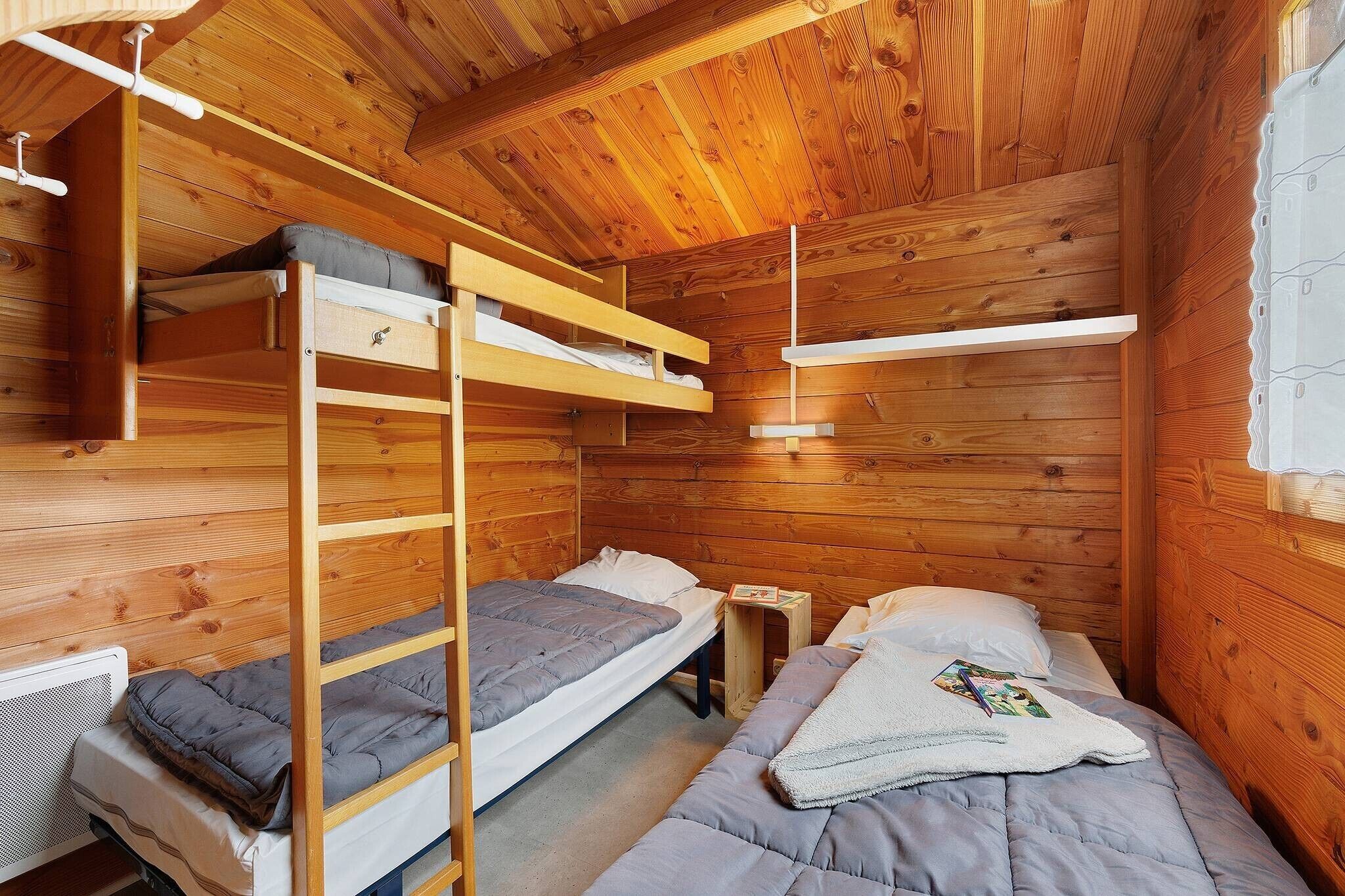 Una habitación tipo cabaña de madera con literas, una mesita y una ventana.