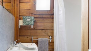 Een badkamer met houten wanden, een witte wastafel, een handdoekhouder en een raam.