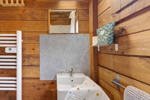 A wooden cabin bathroom with a white sink, mirror, and towel rack. - Chalet “Bois 9” with Shared Pool and Private Terrace (Saint-Gervais)