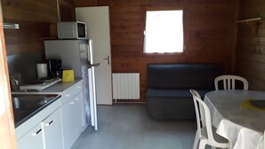 Een praktische keuken met een magnetron, koffiezetapparaat en een kleine eettafel met stoelen.