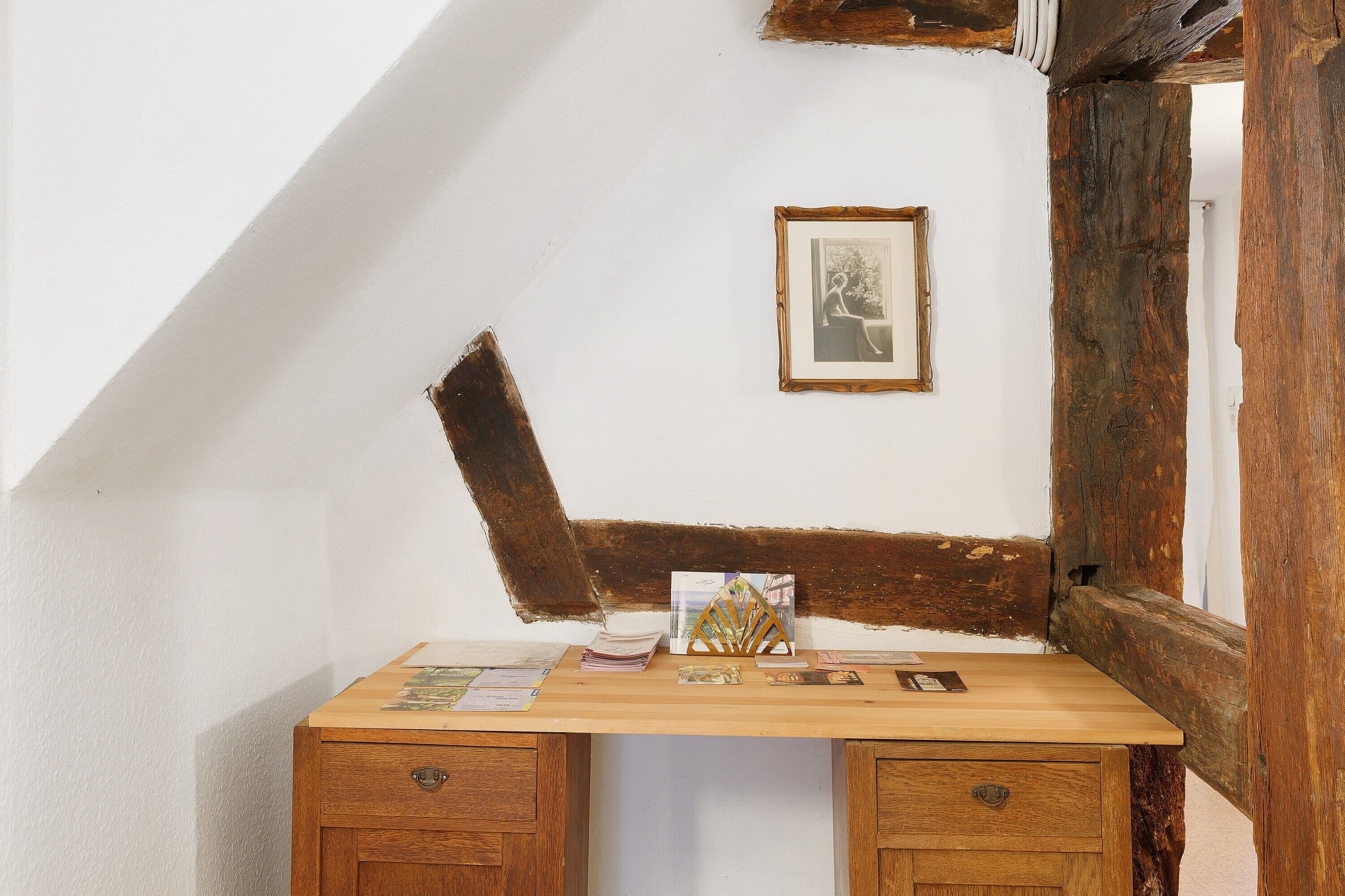 A corner desk with a wooden top, two drawers, and a framed picture on the wall.