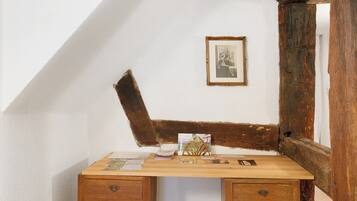 A corner desk with a wooden top, two drawers, and a framed picture on the wall.