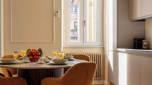 A modern kitchen with a dining area, a window with curtains, and a radiator. - DEZA Colosseum view (Roma)