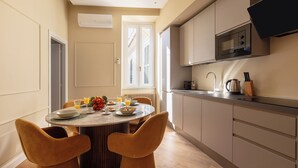 A modern kitchen with a dining area, featuring a round table with chairs, a microwave, and a coffee maker. - DEZA Colosseum view (Roma)