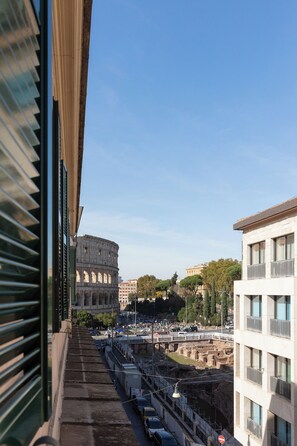 A view from a window overlooking the Colosseum, with modern buildings and a clear sky. - DEZA Colosseum view (Roma)