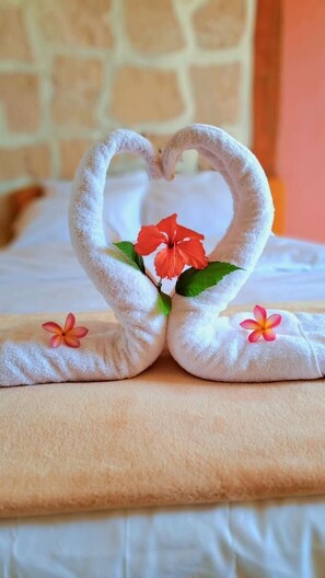 Una cama con una toalla dispuesta en forma de corazón, adornada con flores rojas.