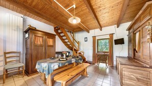 A wooden dining area with a table set for four, a bench, a wooden chair, a staircase, and a television mounted on the wall. - Holiday Home “Petit Gîte - Créac'h-Gourlès” with Wi-Fi (Plouvorn)
