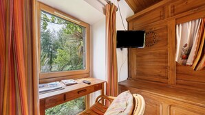 A room with a wooden desk, a chair, a bed with a striped blanket, a TV mounted on the wall, and a window with curtains. - Holiday Home “Petit Gîte - Créac'h-Gourlès” with Wi-Fi (Plouvorn)