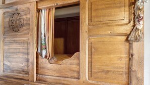 A wooden room with a bed, a window with curtains, and a decorative tassel. - Holiday Home “Petit Gîte - Créac'h-Gourlès” with Wi-Fi (Plouvorn)