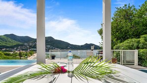 A table set for two with a view of a mountain and a beach. - Villa Blanc de blanc (Les Anses-d'Arlet)