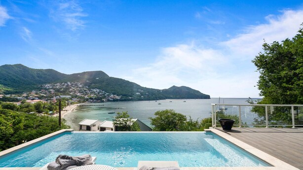 A swimming pool with a view of a coastal town and mountains. - Villa Blanc de blanc (Les Anses-d'Arlet)