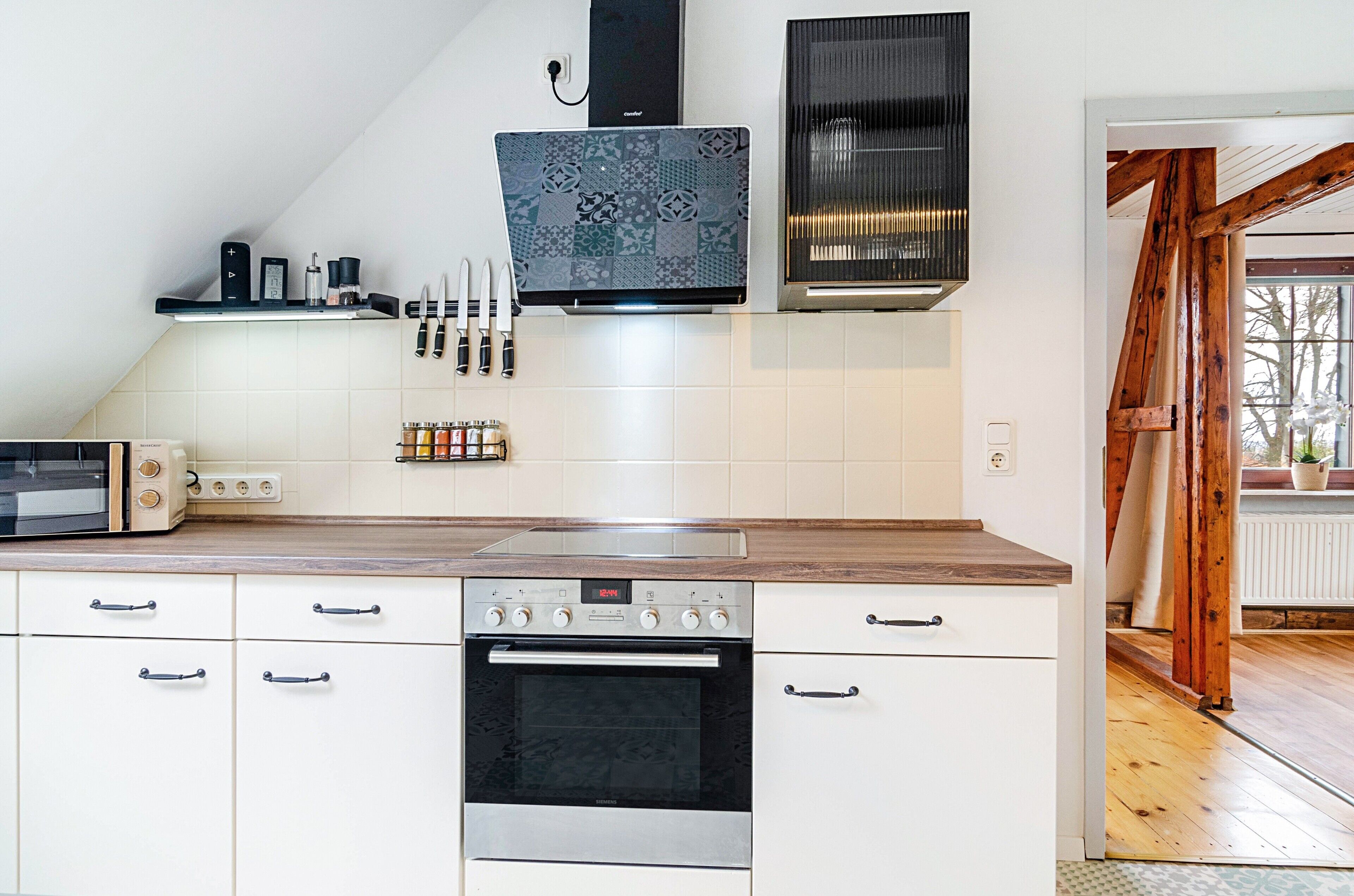 A kitchen with a microwave, oven, and a coffee maker on the countertop.