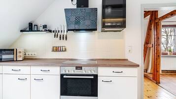 A kitchen with a microwave, oven, and a coffee maker on the countertop.