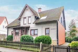 Et toetagers hus med skråtag, en synlig skorsten og et træhegn i forgrunden.