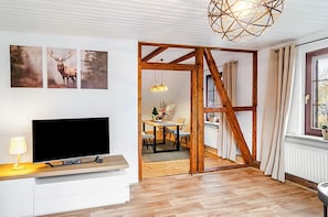 Et moderne interiør med fjernsyn, træbjælker, et spiseområde og et vindue.
