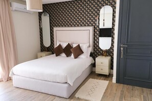 Un dormitorio ordenado con una cama grande, dos mesitas de noche, un aparador y una puerta oscura.