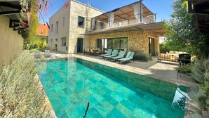 A modern house with a swimming pool, outdoor seating, and a stone facade. - Villa Syria Luxe à Marrakech (Marrakech)