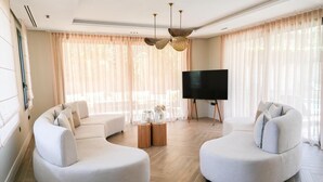 A modern living room with two curved sofas, a flat-screen TV, and a wooden coffee table. - Villa Syria Luxe à Marrakech (Marrakech)