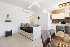 Ein moderner, kompakter Wohnraum mit Bett, Esstisch und Küchenzeile.
