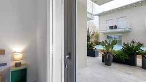 Un bâtiment moderne doté d’un balcon, d’une piscine et de plantes en pot.