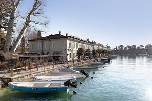 Una hilera de barcos amarrados a la orilla, un edificio con un letrero que dice 'PAVILLON' y un cielo despejado.