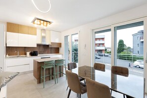Eine moderne Küche mit Essbereich, großen Fenstern und Blick auf die Straße.