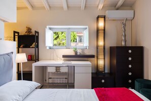 A bedroom with a bed, a desk with a chair, a dresser, a lamp, a window, and a decorative tree sculpture. - Carmelina Home 2 by Wonderful Italy (Mascali)