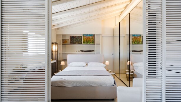 Une chambre à coucher moderne avec un grand lit, des lampes de chevet, une table de chevet et un miroir.