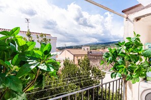 A balcony with a view of a cityscape, including buildings and a mountain in the distance. - Carmelina Home 2 by Wonderful Italy (Mascali)
