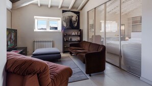 Un salon moderne doté d’un haut plafond, d’une grande fenêtre, d’un canapé, d’une table basse et d’une bibliothèque.