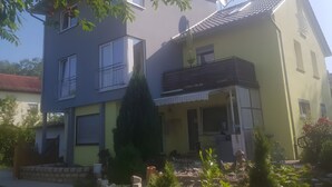 A two-story building with a balcony, a satellite dish, and a small garden area.