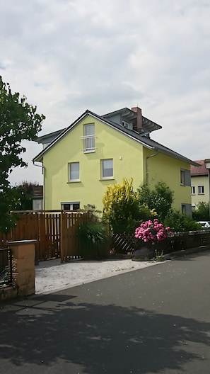 Ein zweistöckiges Haus mit flachem Dach, einem sichtbaren Schornstein und einer befestigten Auffahrt.