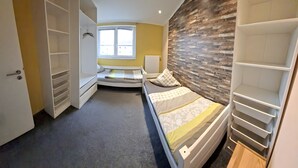 A compact room with a bed, a wardrobe, and a window with a view.