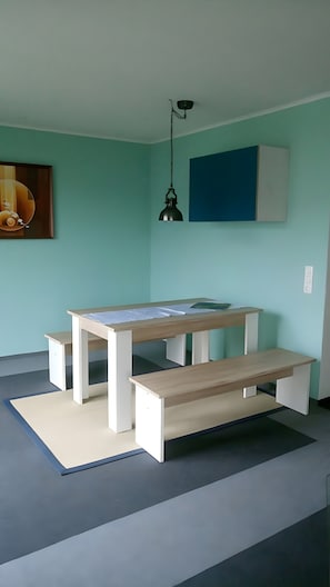 Ein Zimmer mit Holztisch, Bänken, einer Hängelampe und einem Wandlichtschalter.