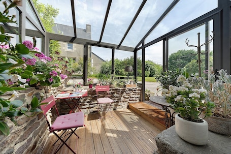 A conservatory with a wooden deck, stone wall, and potted plants.. Country House 'Chambre Jérôme' with Wi-Fi