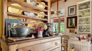 Una cocina con estantes de madera, una estufa antigua y diversos utensilios de cocina.