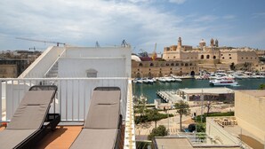 A rooftop terrace with sun loungers overlooking a marina with boats and historic buildings. - Traditional Townhouse - Rooftop Seaviews (Cospicua)
