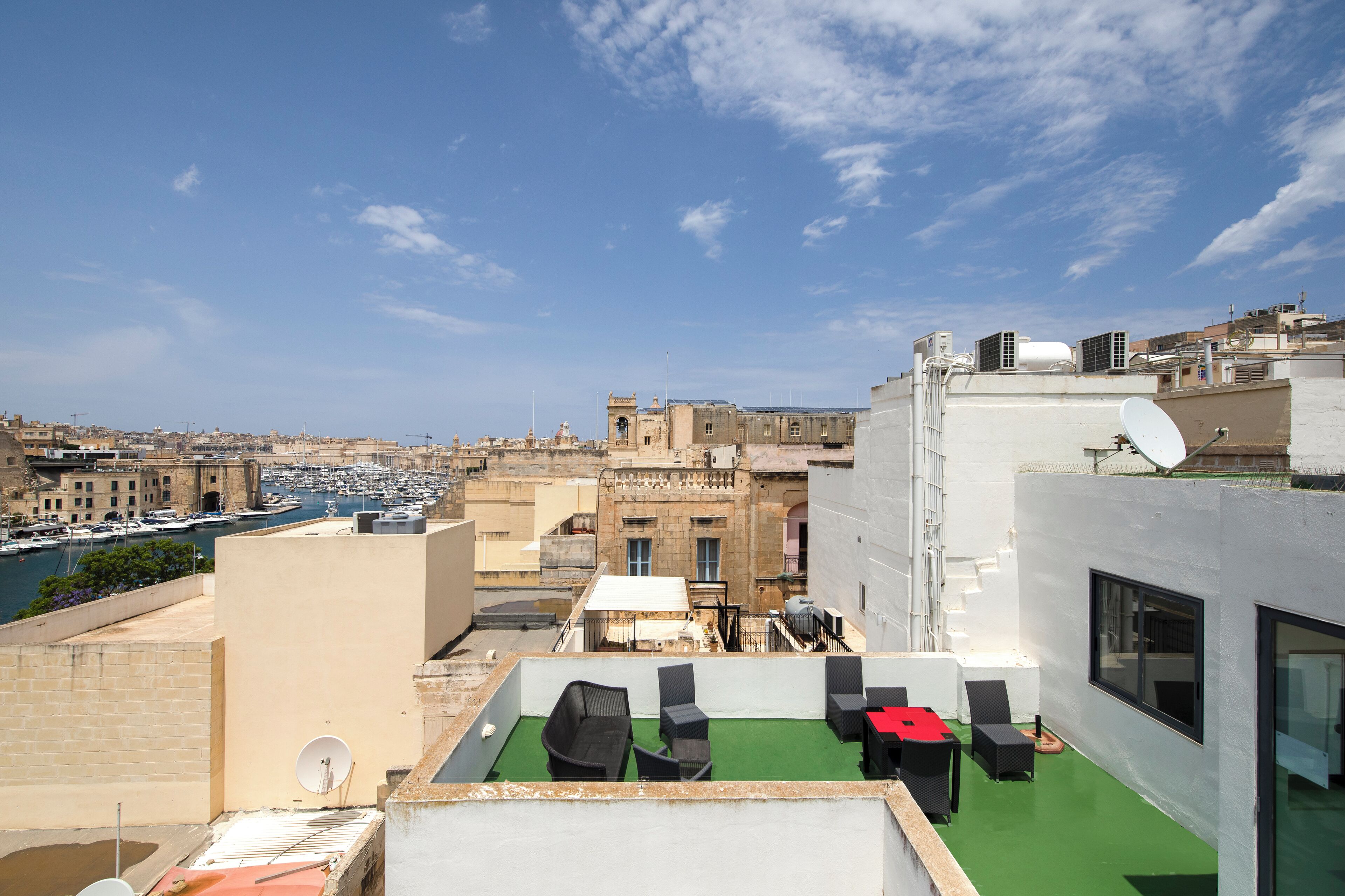 A rooftop terrace with outdoor seating, a view of the marina, and buildings in the background.