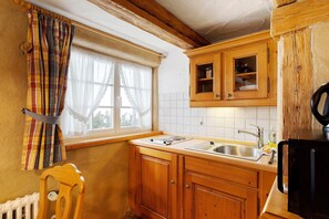 Uma cozinha com armários de madeira, uma janela com cortinas, uma pia e um fogão.