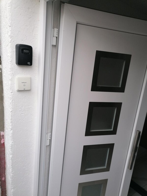 A white door with three rectangular windows and a doorbell.