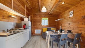 Ein Holzblockhaus-Innenraum mit Küche, Essbereich und einem Fenster.