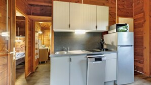 Een compacte keuken met houten wanden, een inbouwvaatwasser en een koelkast.