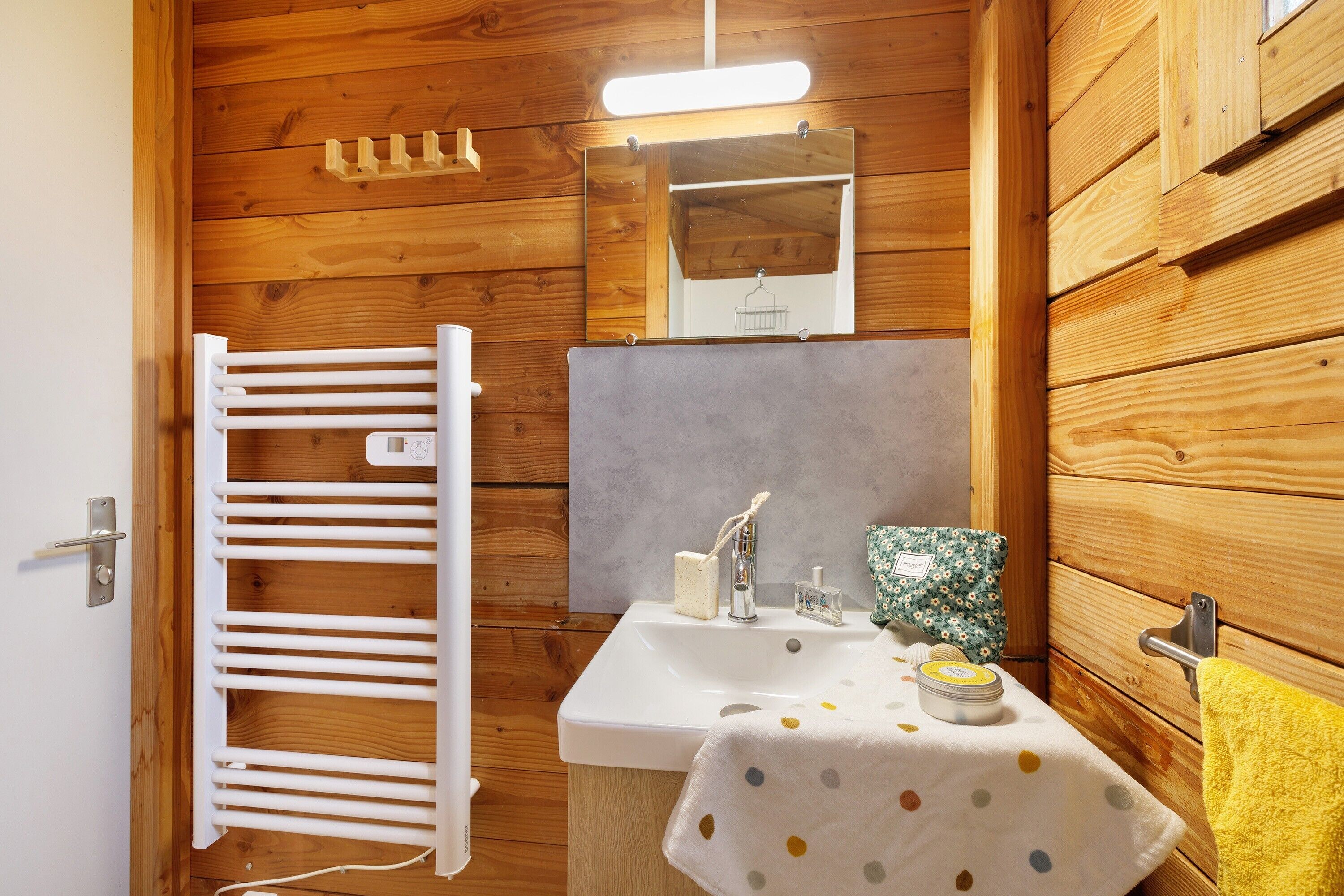 A wooden-paneled bathroom with a white sink, a towel, and a mirror.