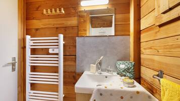 Un baño con paneles de madera, un lavabo blanco, una toalla y un espejo.
